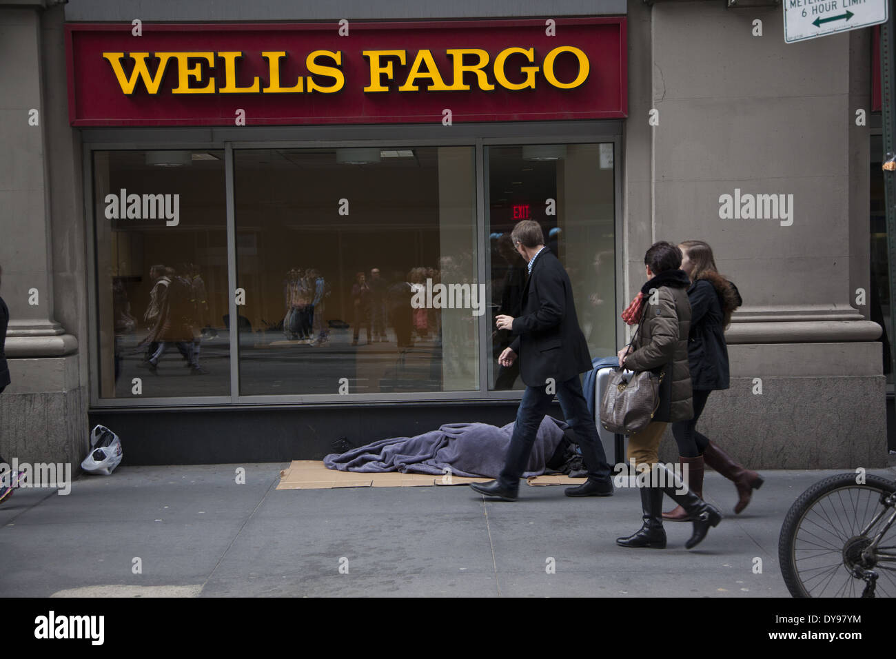 Die Menschen gehen übrigens kaum zu bemerken, ein Obdachloser schläft vor einer Bank in Midtown Manhattan. Stockfoto