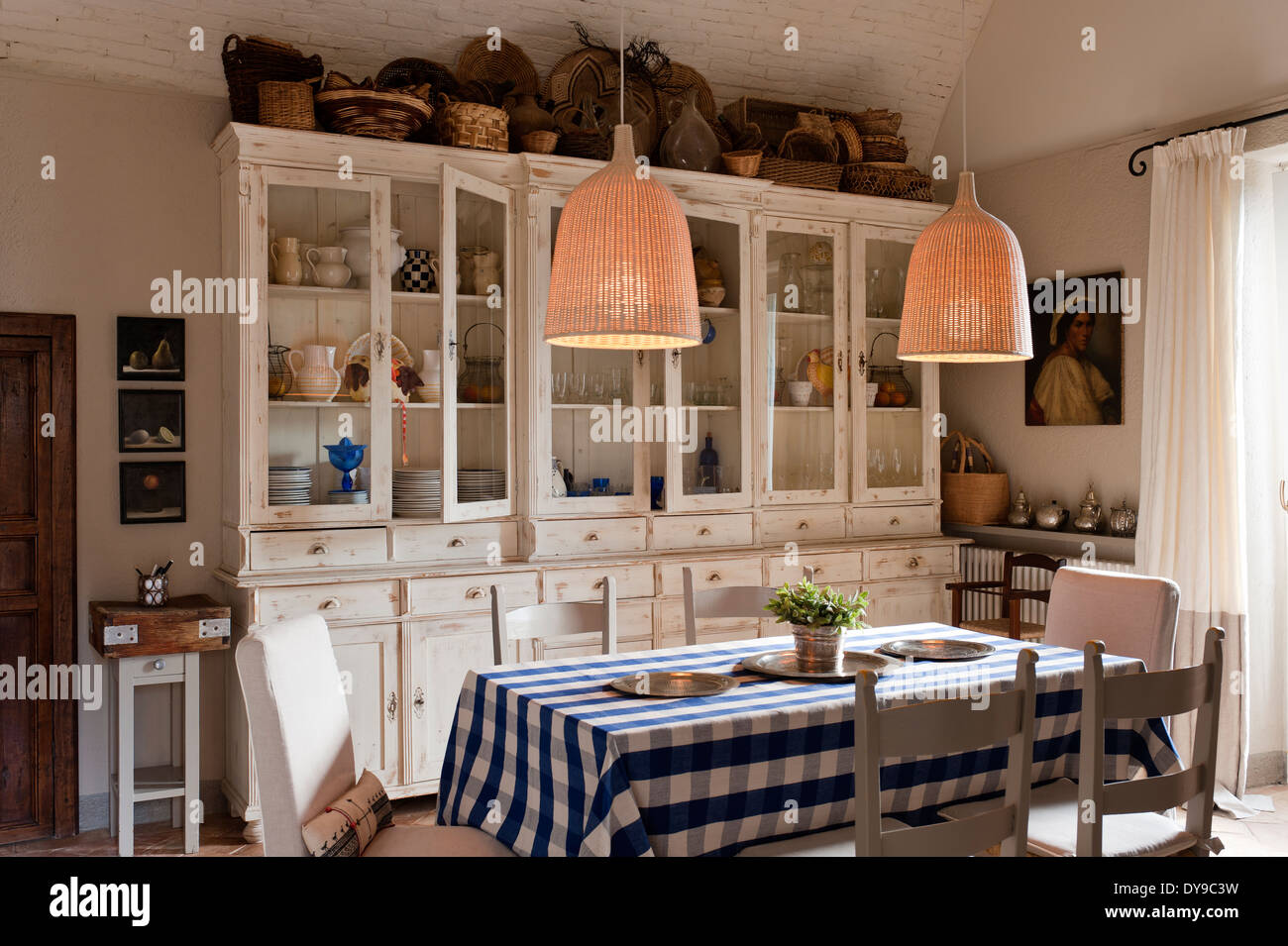 Rustikale Landhausküche mit französischem Schränke, aufgegebenes Blaue Tischdecke und gesponnene Flechtweide Pendelleuchten Stockfoto
