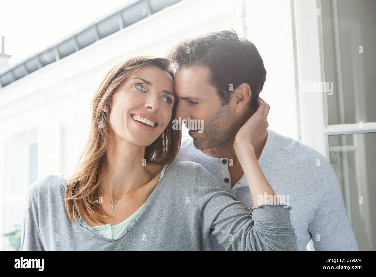 Paar Flüstern und lächelnd durch Fenster Stockfoto