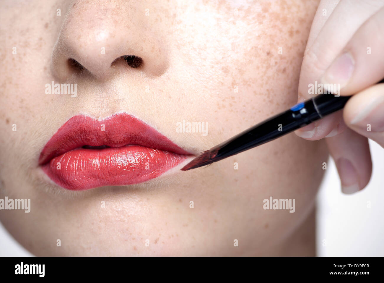 Junge Frau Auftragen von Lippenstift mit Pinsel, Nahaufnahme Stockfoto
