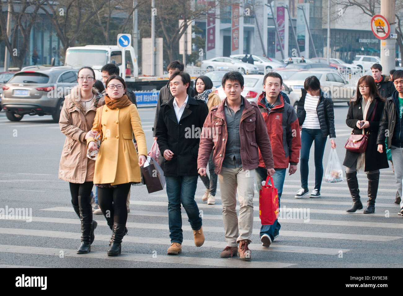 junge Chinesen zu Fuß auf Fußgängerüberweg in Peking, China Stockfoto