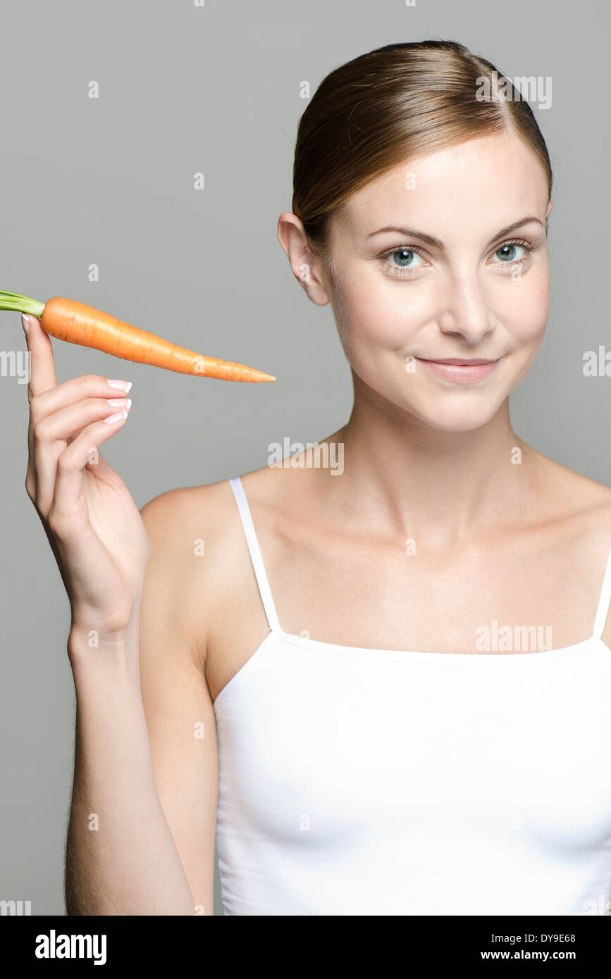 Junge Frau hält rohe Karotte Stockfoto
