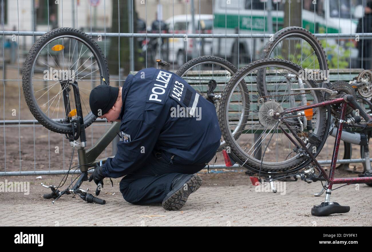 Berlin, Deutschland. 9. April 2014. Ein Polizist prüft Fahrräder, die in der ehemaligen Flüchtlingslager am Oranienplatz in Berlin, Deutschland, 9. April 2014 gefunden wurden. Einen Tag nach der Räumung des Lagers Polizisten sicherte den Platz, während Mitarbeiter der Berliner Stadtreinigung (BSR) die Überreste des Lagers entfernen. Die meisten der Asylsuchenden verließ das Camp freiwillig am Vortag. Foto: Paul Zinken/Dpa/Alamy Live News Stockfoto