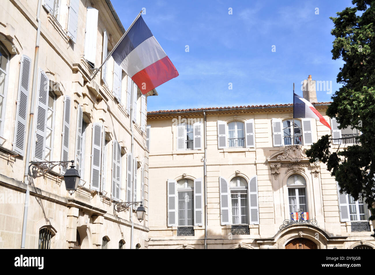 Die französische Flagge fliegt über die elegante Fassade des Sous-Prefecture (Verwaltungsgebäude) in Arles, Frankreich. Stockfoto