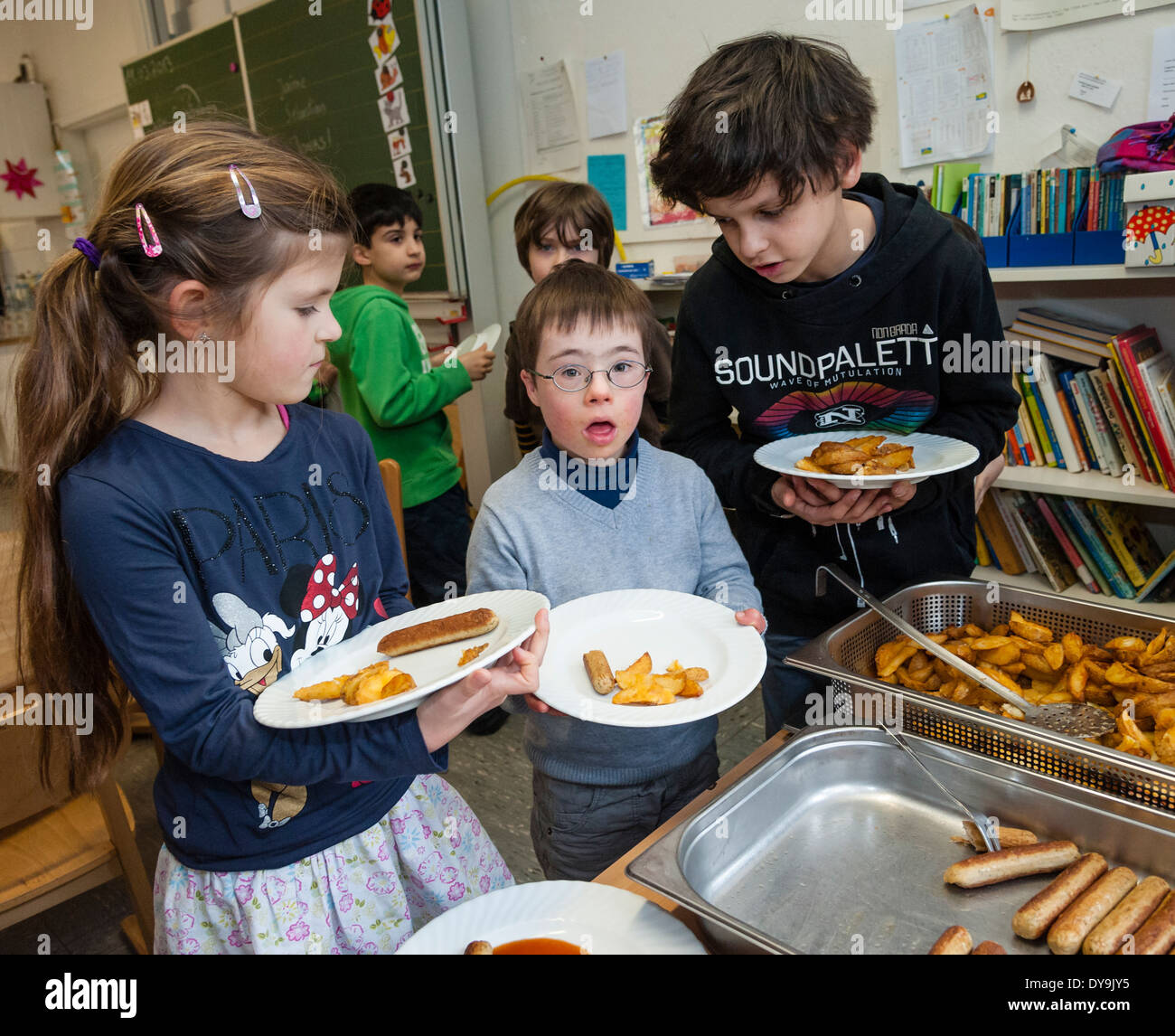 Nicht behinderte und behinderte Schüler (in diesem Fall ein Junge mit Down-Syndrom) haben Mittagessen zusammen in ihrem Klassenzimmer. Stockfoto