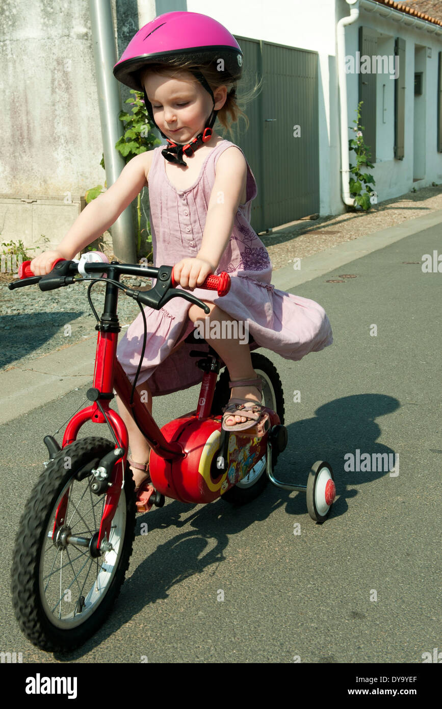 Mädchen Reiten Fahrrad mit Stützrädern Stockfoto