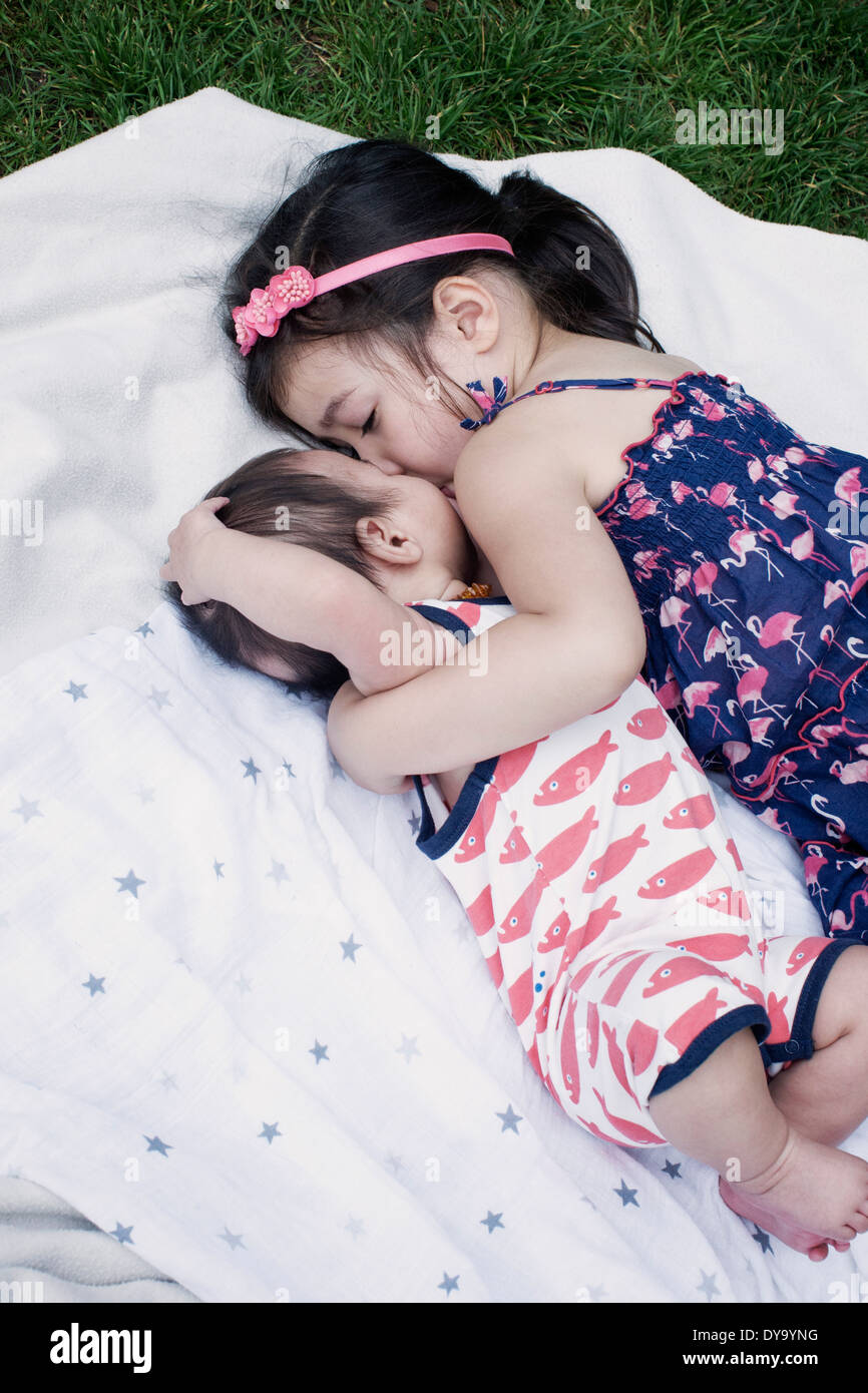 Kleines Mädchen mit kleinen Bruder auf der Decke im freien liegend Stockfoto