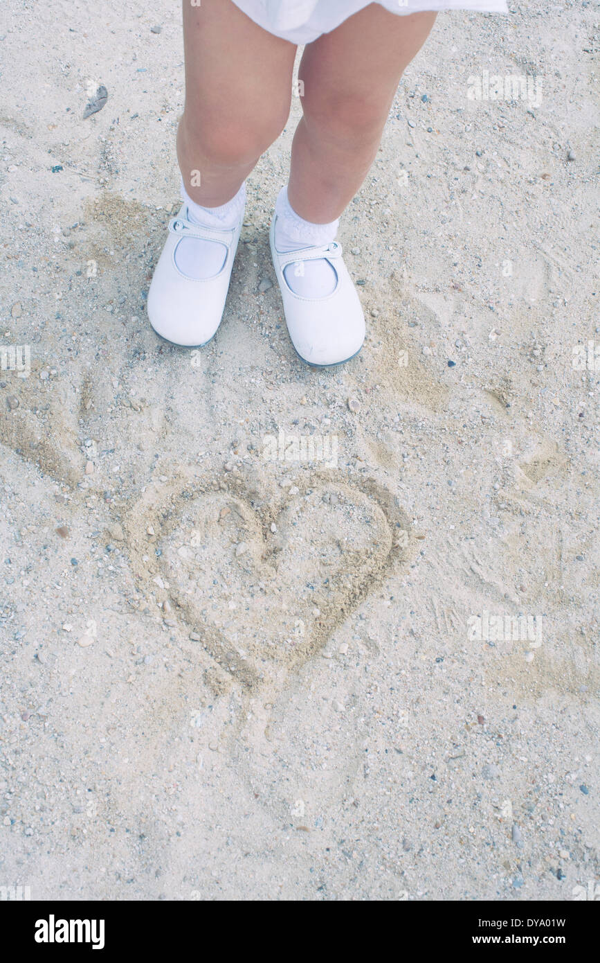 Kind stehend über Herz in Sand gezeichnet Stockfoto