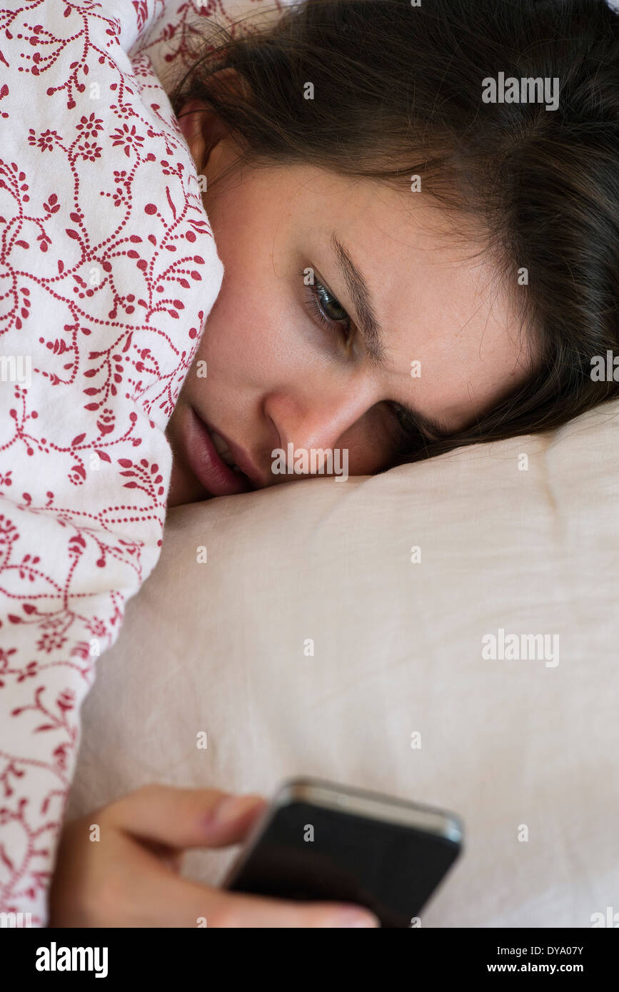 Frau liegend Bett Smartphone mit unglücklichen Gesichtsausdruck betrachten Stockfoto