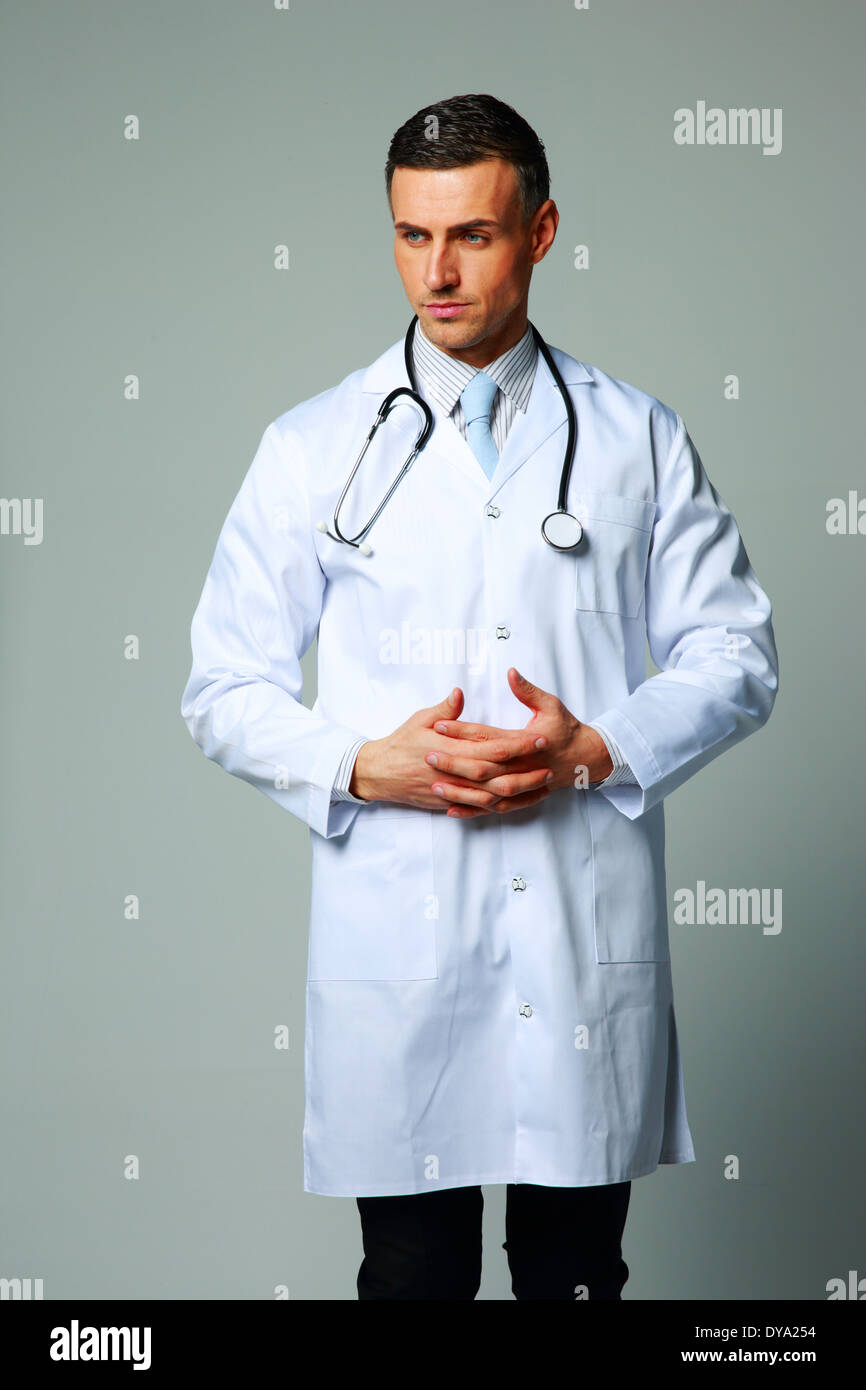 Porträt von einer nachdenklichen männlichen Arzt auf grauem Hintergrund Stockfoto