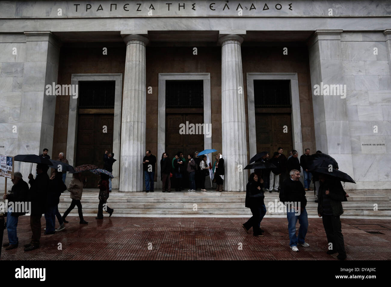 Athen, Griechenland. 11. April 2014. Demonstranten versucht, sich vor dem Regen in den Eingang des Ortsverbandes Bank von Griechenland zu schützen. Bildnachweis: Konstantinos Tsakalidis/Alamy Live-Nachrichten Stockfoto
