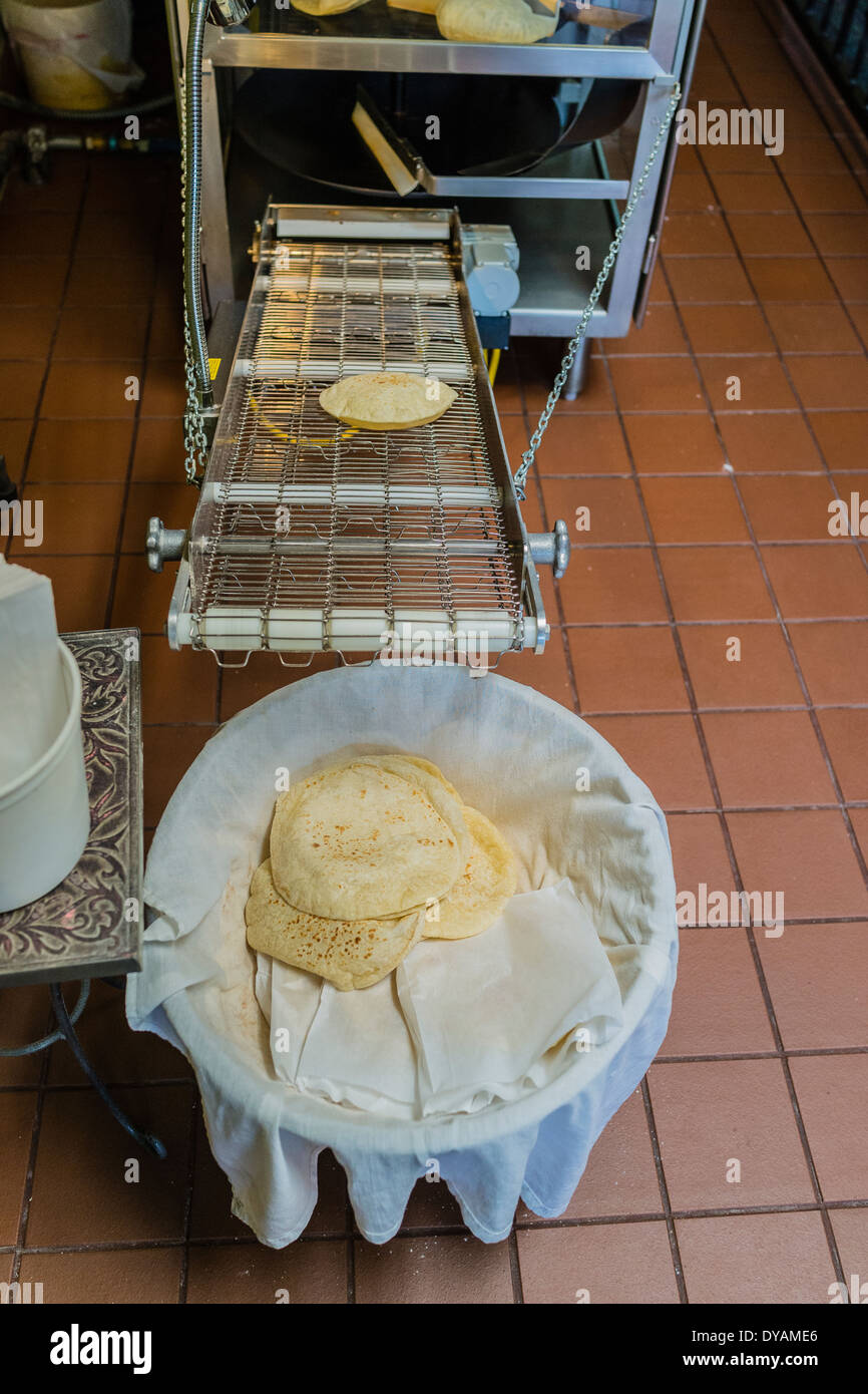Weizen-Tortillas bestehen in einer Maschine sind kommt aus der Maschine auf einem Förderband in einem Restaurant in Yuba City, Kalifornien. Stockfoto