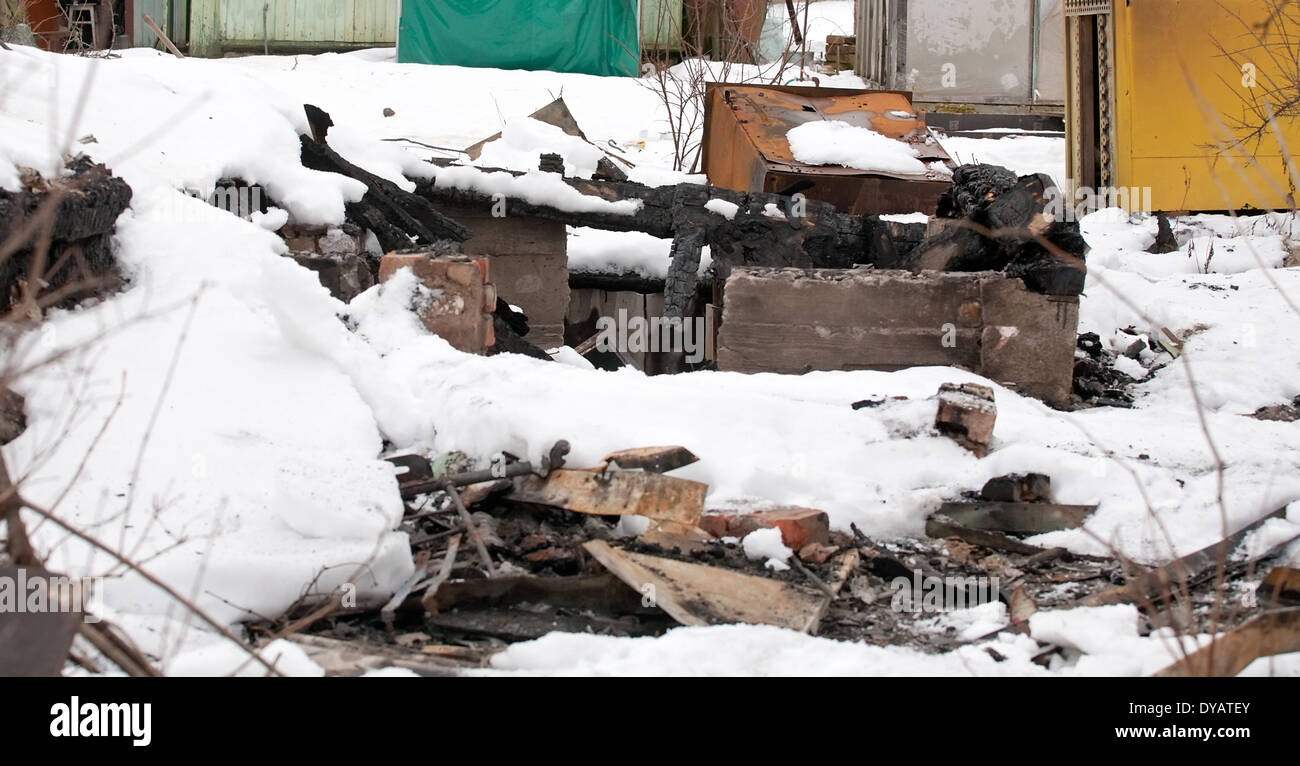 verbrannte Ruinen des Hauses mit Müll und Abfall bedeckt mit Schnee Stockfoto