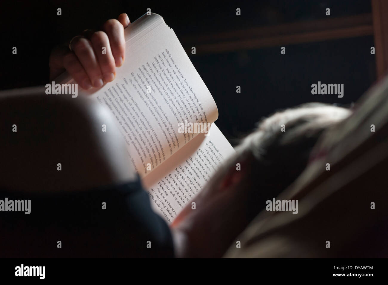 Eine Frau ist in ihrem Bett liegen und ein Buch als Vortrag vor dem Schlafengehen. Stockfoto