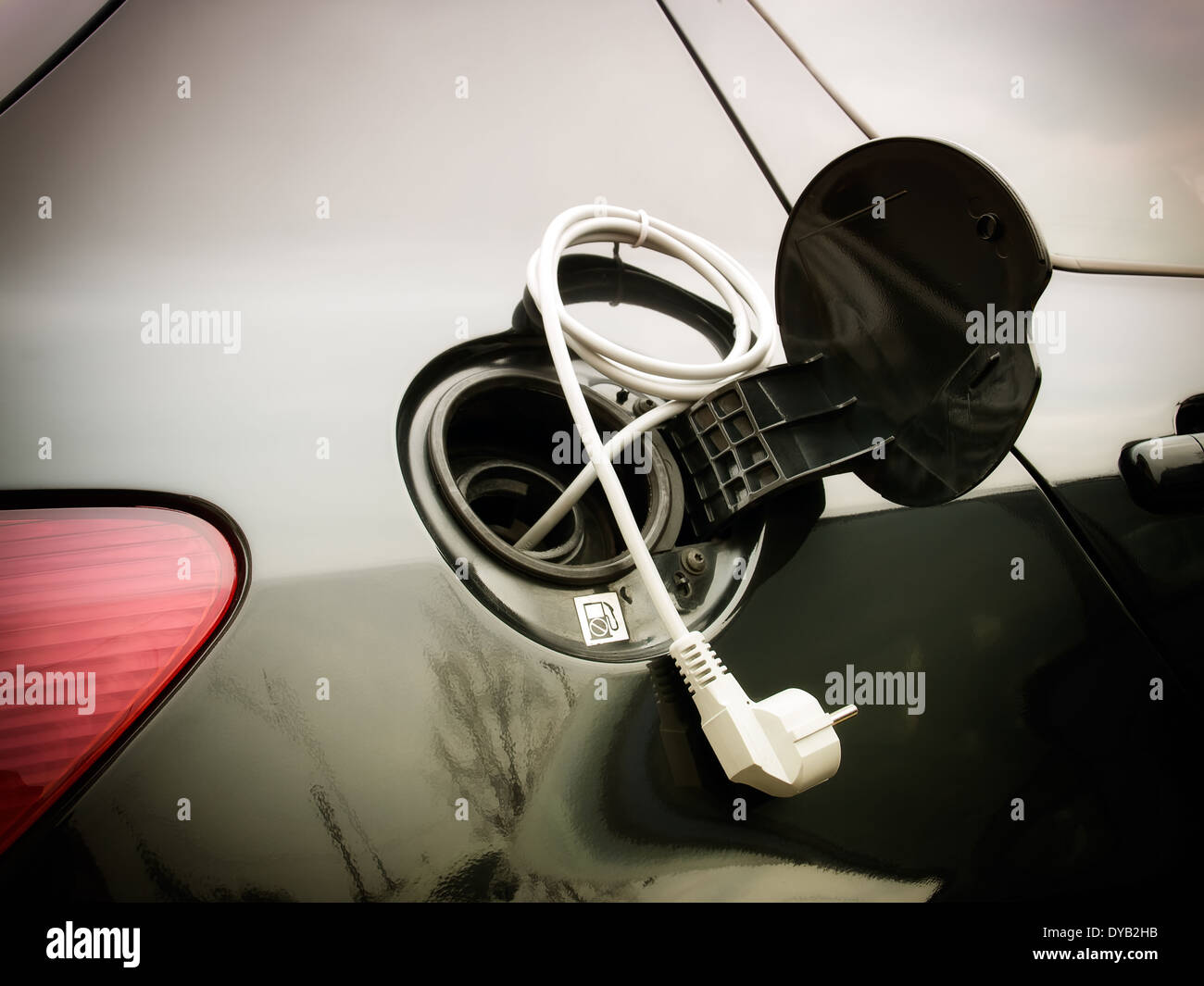 Elektrische Kabel mit einem Stecker verbunden mit einem Auto-Tank. Stockfoto