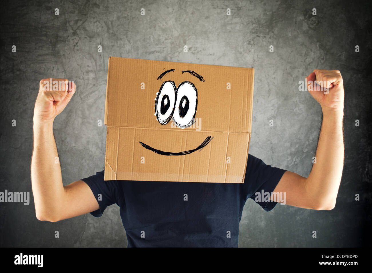 Glücklich lächelnden Mann mit Karton auf seinen Kopf und erhobenen Fäusten um den Sieg. Konzept des Gewinnens. Stockfoto
