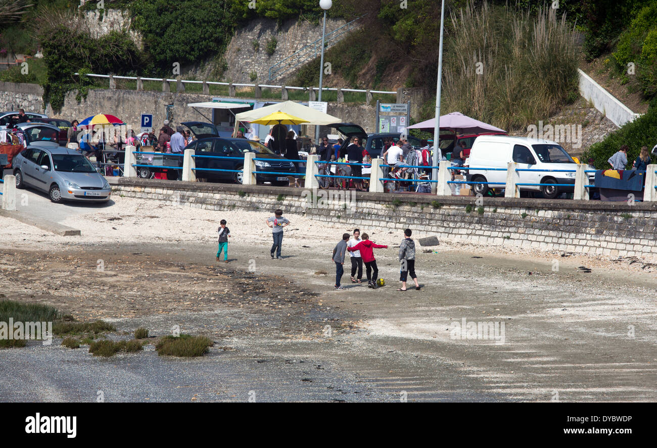 Kinder spielen Fußball am Strand mit Brocante Markt Stockfoto