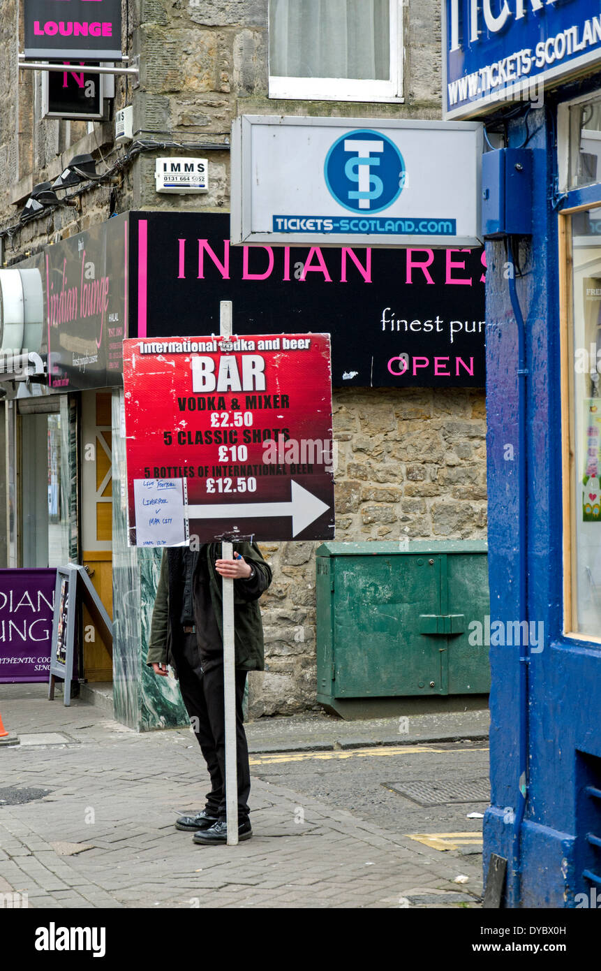 Ein junger Mann mit einem Schild Werbung billig trinken. Stockfoto