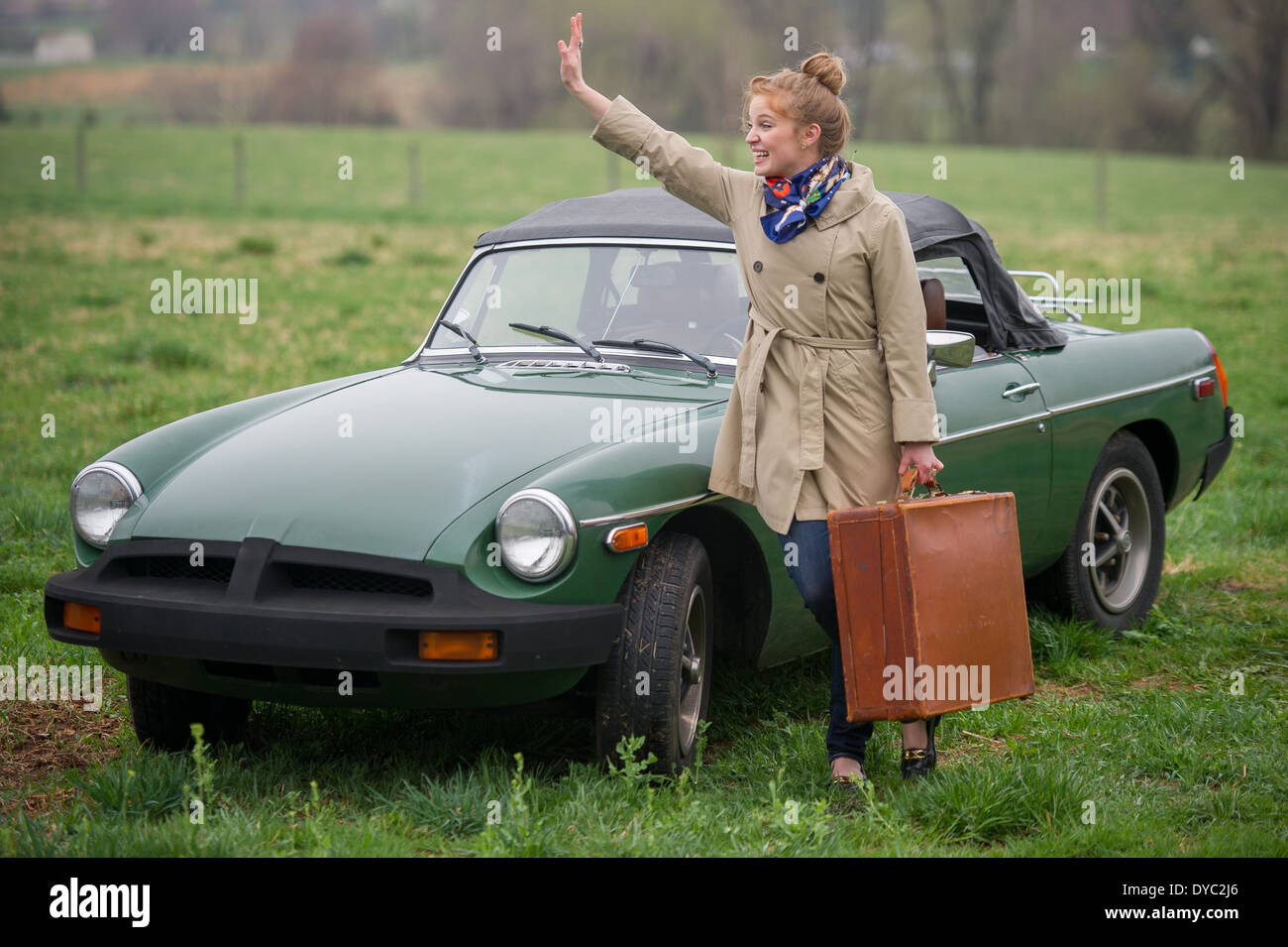 Frau mit gepackten Koffern auf Reise neben klassischen britischen Sportwagen Stockfoto