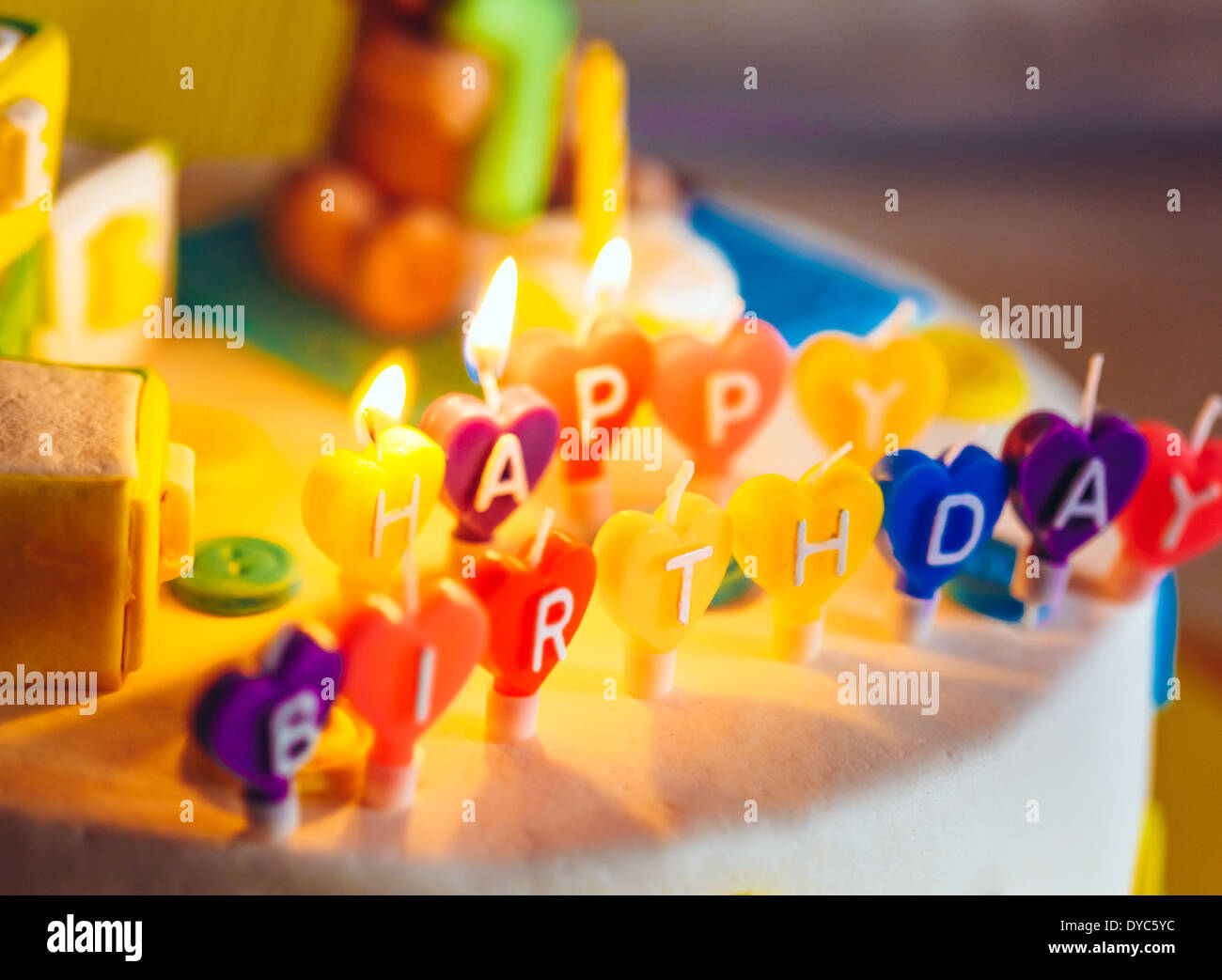 Happy Birthday geschrieben in Kerzen auf bunten Kuchen Hintergrund Stockfoto