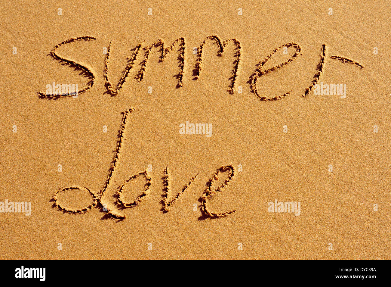 der Text Summer Love, geschrieben in den Sand des Strandes Stockfoto