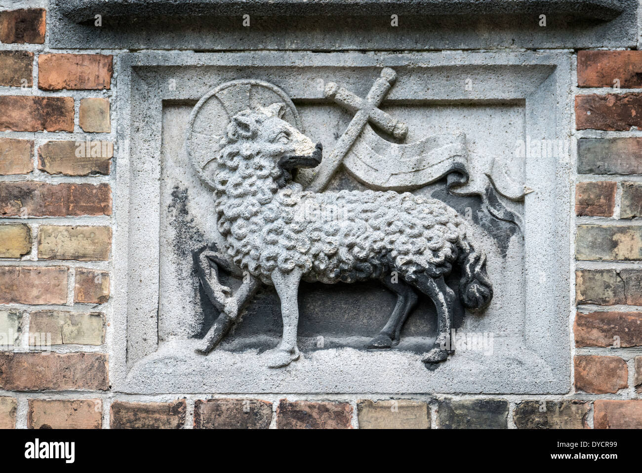 Agnus Dei Lamm Gottes Tafel Sint-Janshospitaal Brügge Belgien // BRÜGGE, Belgien — Eine geschnitzte Tafel mit dem Agnus Dei (Lamm Gottes), Symbol des Heiligen Johannes des Täufers, ziert das Äußere des Sint-Janshospitaal (altes Johanniskrankenhaus). Dieses religiöse Emblem, kombiniert mit einem Kreuz, kennzeichnet die Widmung des Gebäudes an seinen schutzheiligen. Das architektonische Detail repräsentiert die doppelte Rolle des Krankenhauses sowohl als medizinische als auch als religiöse Institution. Stockfoto