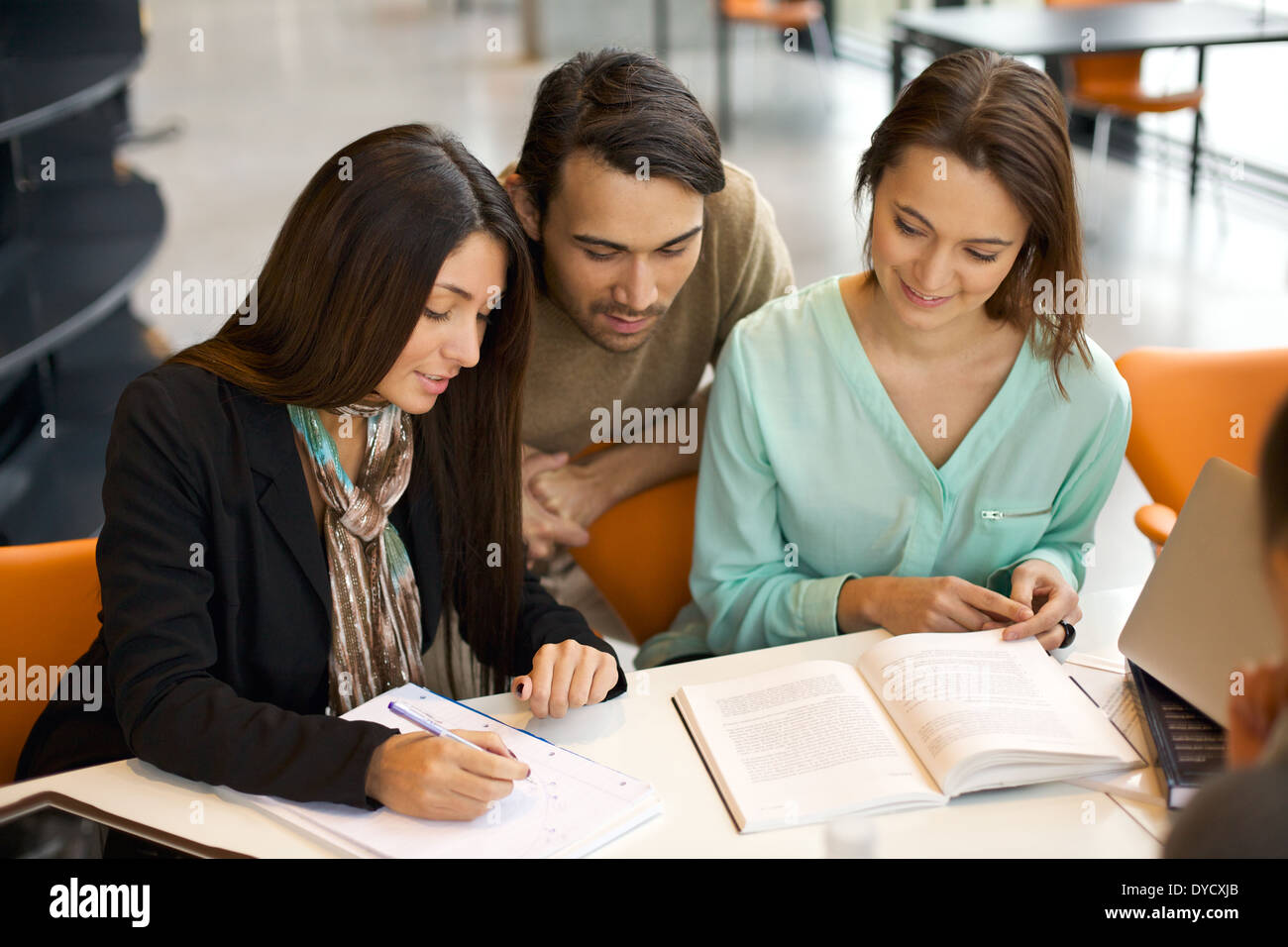 Junge Menschen, die am Tisch sitzen und an Schulprojekten in der Bibliothek arbeiten. universitätsstudenten, die sich aus Büchern für das Studium beziehen. Stockfoto