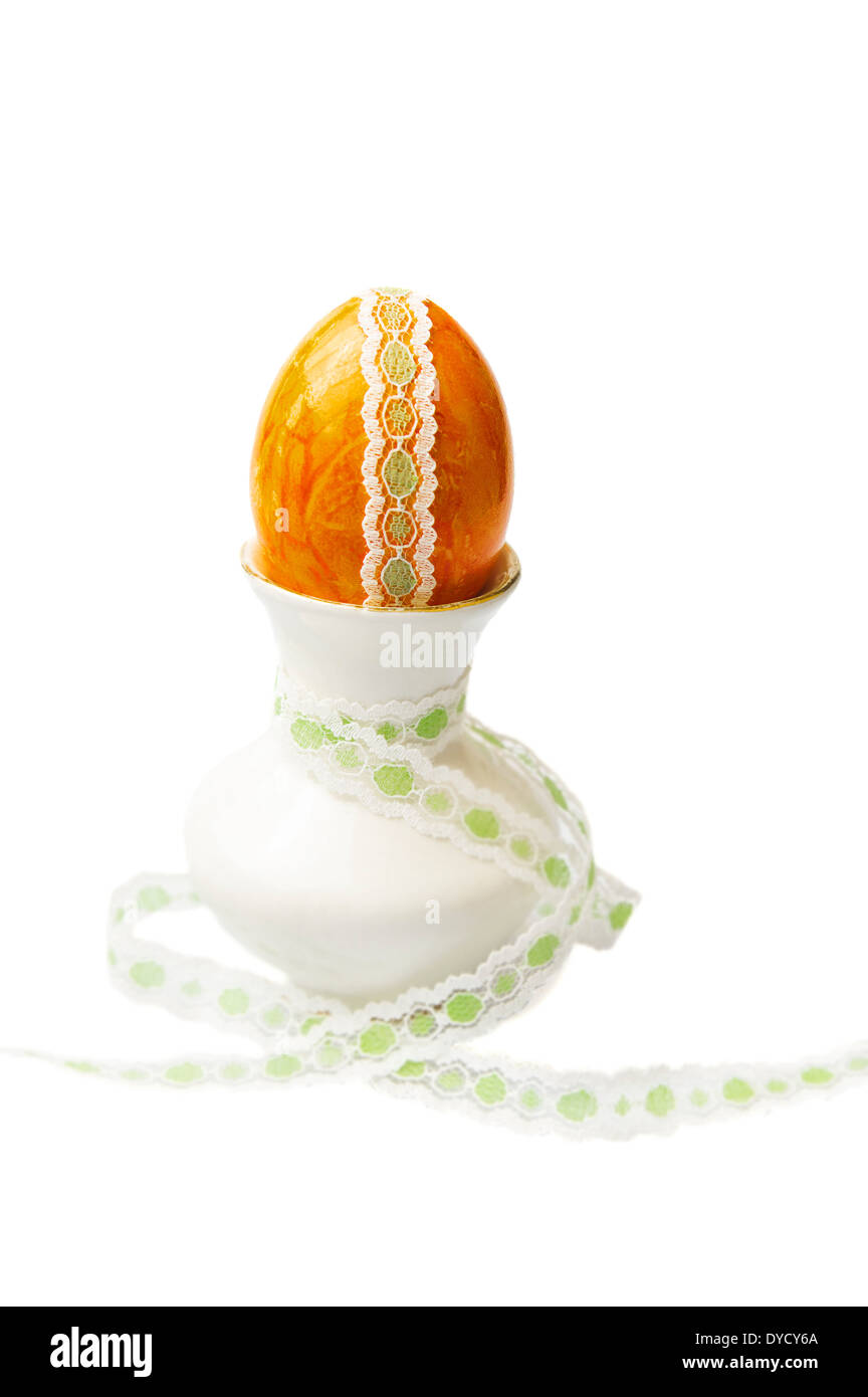 Orange Ostern Deko Ei mit Spitzen Drum und dran in Minivase auf weißem Hintergrund Stockfoto