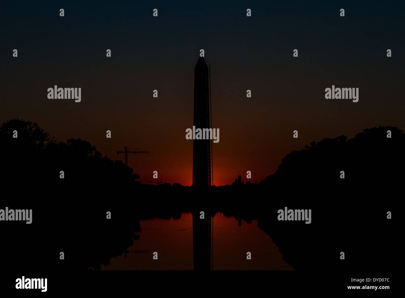 Die Sonne unter dem Horizont wirft eine Morgendämmerung leuchten hinter der Basis des Washington Monument. Blick von Lincoln Memorial Reflecting Pool. Diese Aufnahme wurde während der Herbstanfang aufgenommen, wenn die Sonne steigt direkt nach Osten und daher reiht sich mit der National Mall. Stockfoto