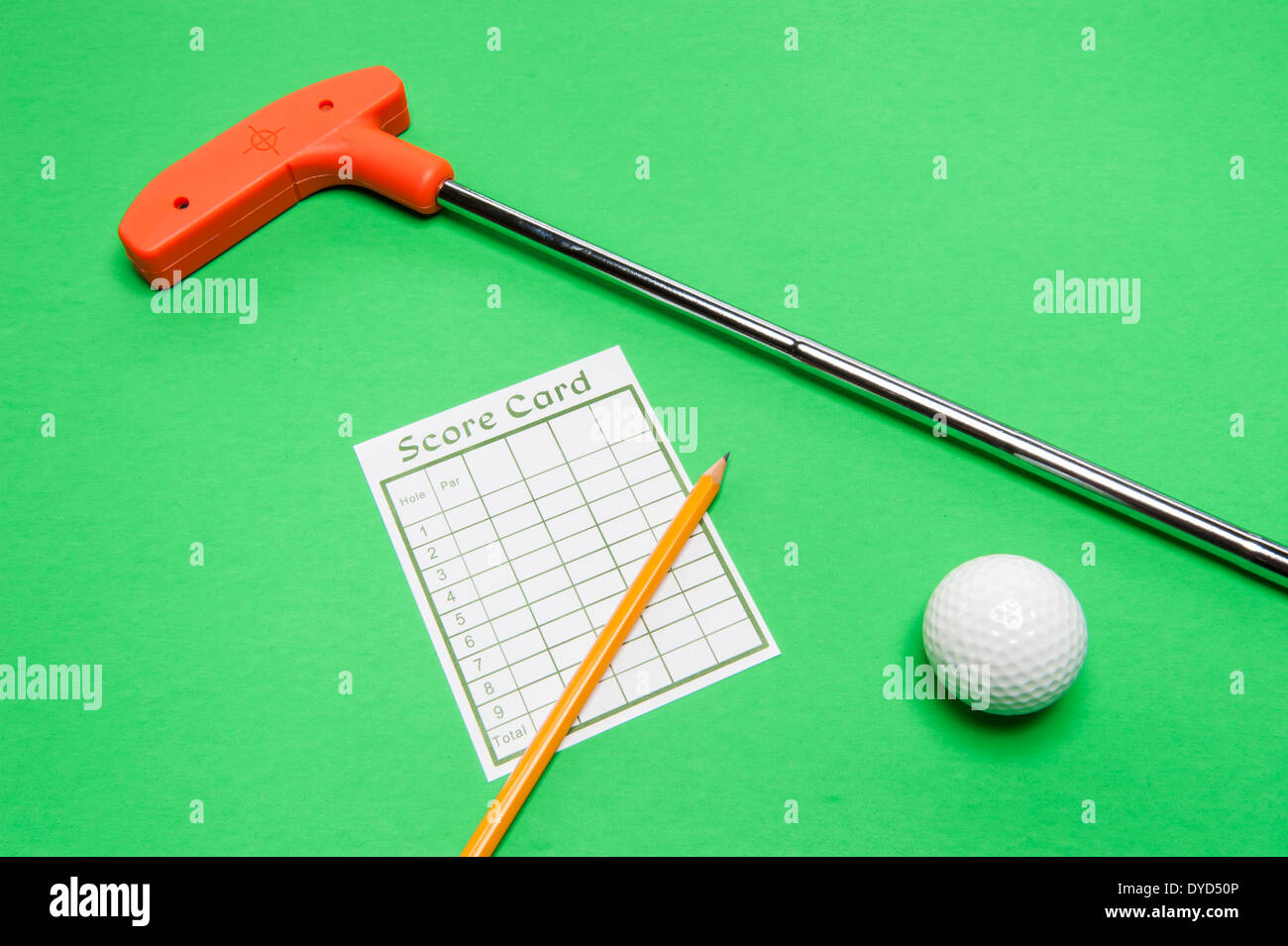 Mini Golf-Club mit Scorekarte, Ball und Bleistift auf grünem Hintergrund Stockfoto