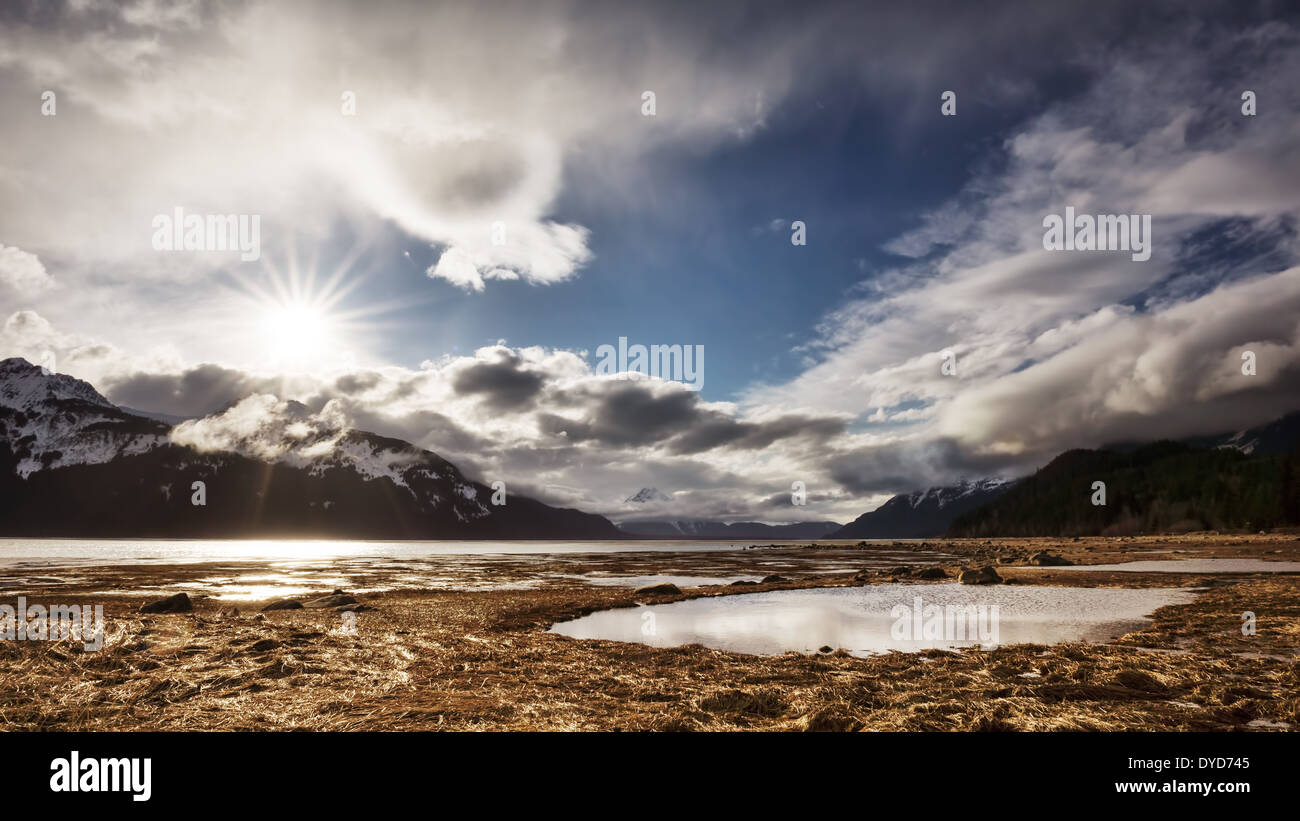 Sunburst mit Wolken in der Nähe der Chilkat Inlet in Southeast Alaska über Berge. Stockfoto