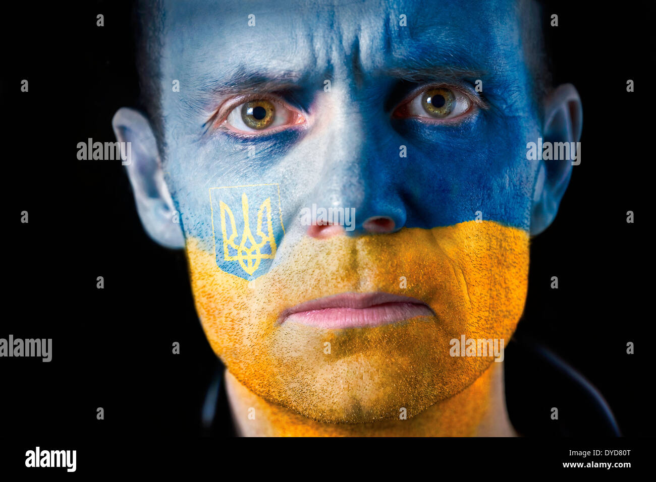 Ein intensiver Blick von einem Mann mit ihrem Gesicht gemalt mit der ukrainischen Flagge. Stockfoto