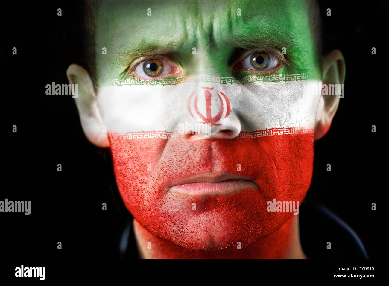 Ein intensiver Blick von einem Mann mit ihrem Gesicht gemalt mit der iranischen Flagge. Stockfoto