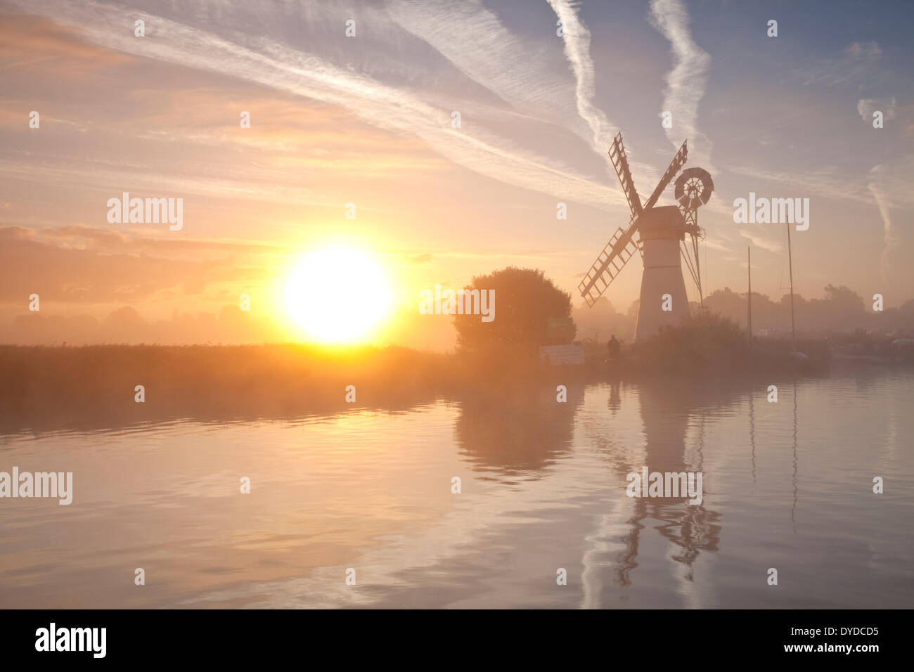 Thurne Mill bei Sonnenaufgang an einem nebligen Morgen auf den Norfolk Broads. Stockfoto