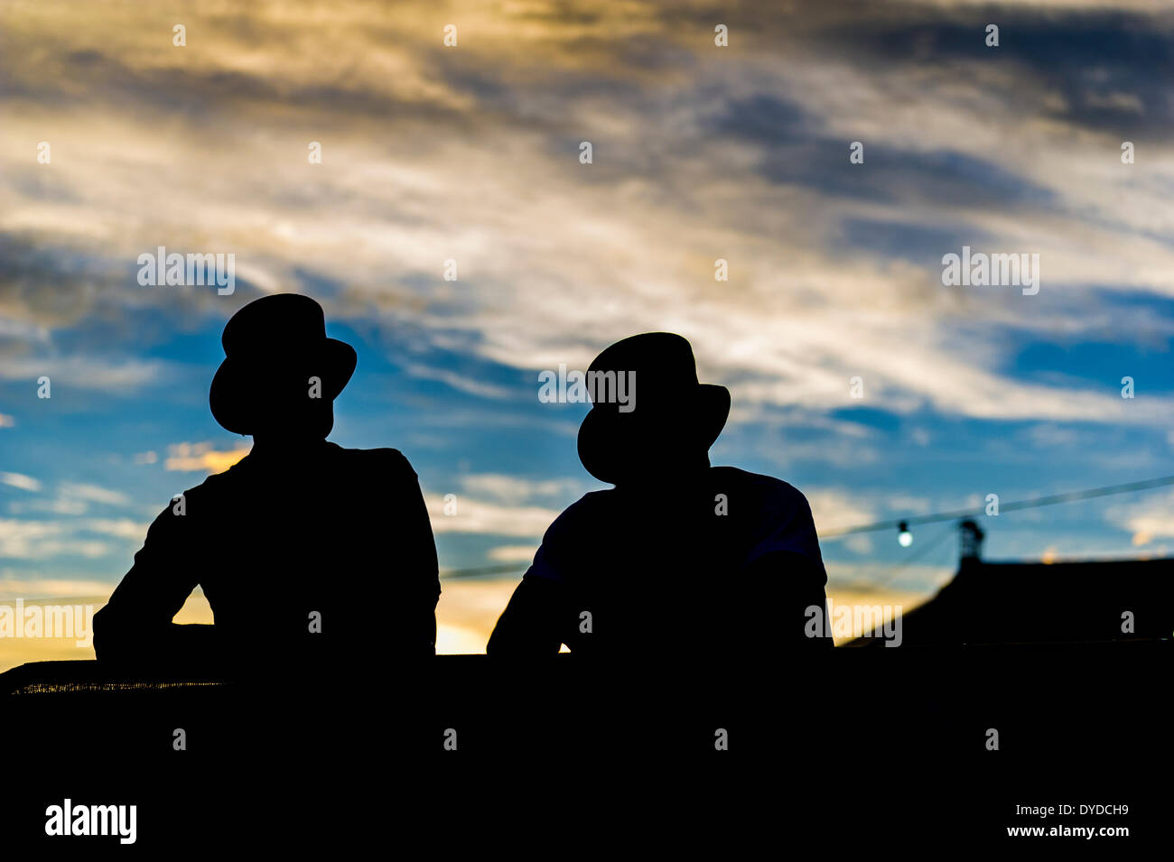 Die Silhouette der beiden BesucherInnen Spitze Hüte tragen, auf dem Brownstock Festival in Essex. Stockfoto