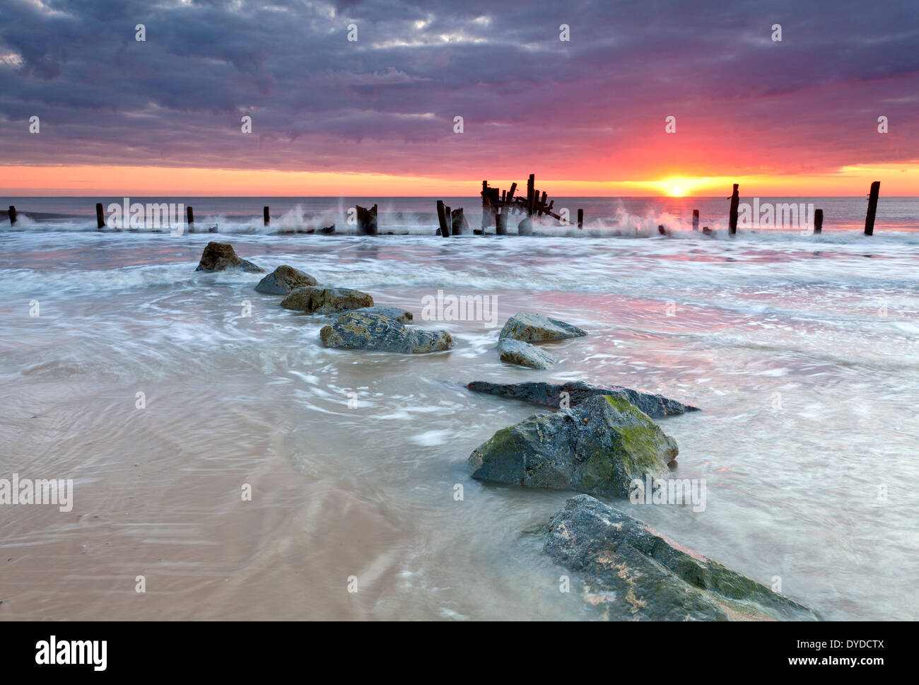 Happisburgh Strand und die verfallenen Küstenschutzes bei Sonnenaufgang an der Küste von Norfolk. Stockfoto
