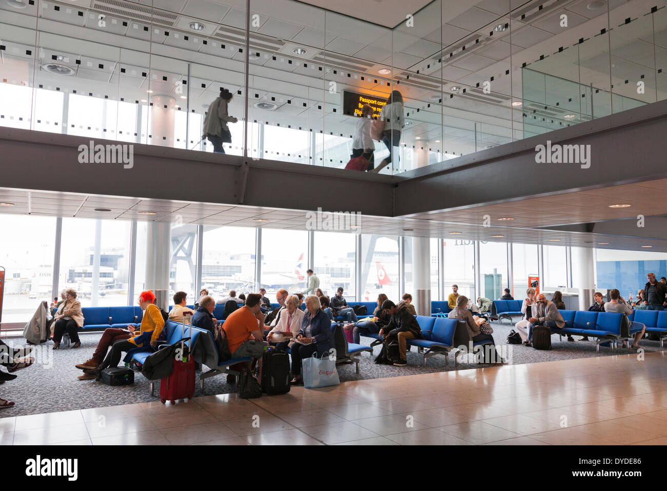 Passagiere warten in einer Flughafen-Abflug-Lounge unter einen Ankünfte-Korridor. Stockfoto