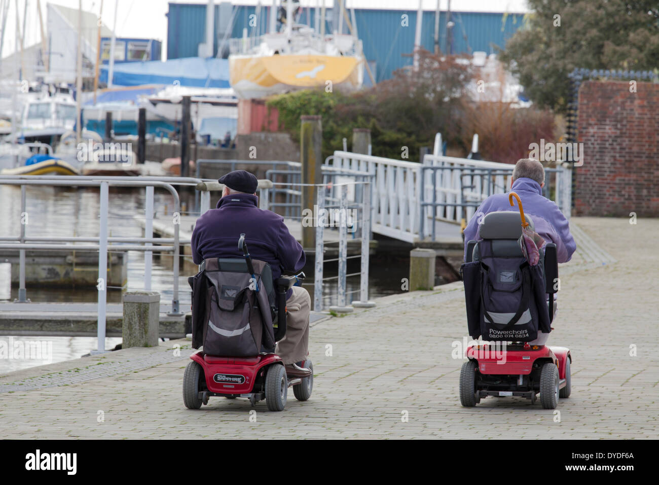 Zwei Männer im motorisierten Rollstuhl auf dem Kai in Lymington. Stockfoto