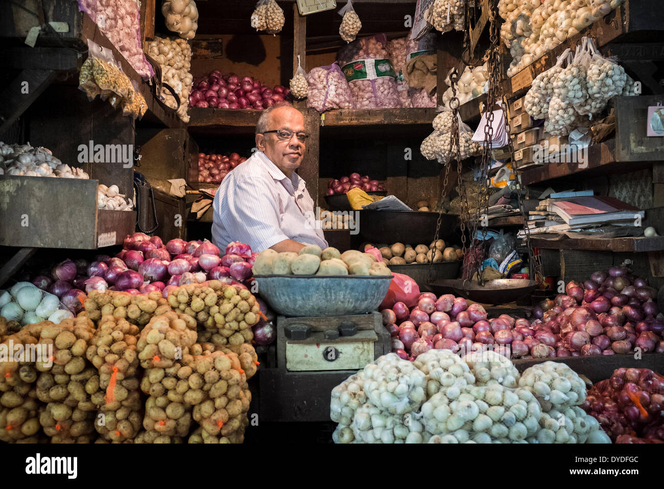 Ein Gemüsehändler sitzt in seinem Laden in einem Großhandel Gemüsemarkt. Stockfoto