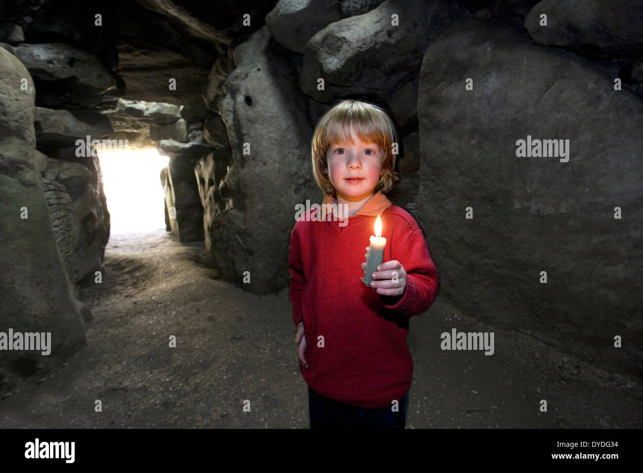 Ein vier Jahre alter Junge erforscht West Kennet Grabkammer mit einer Kerze. Stockfoto