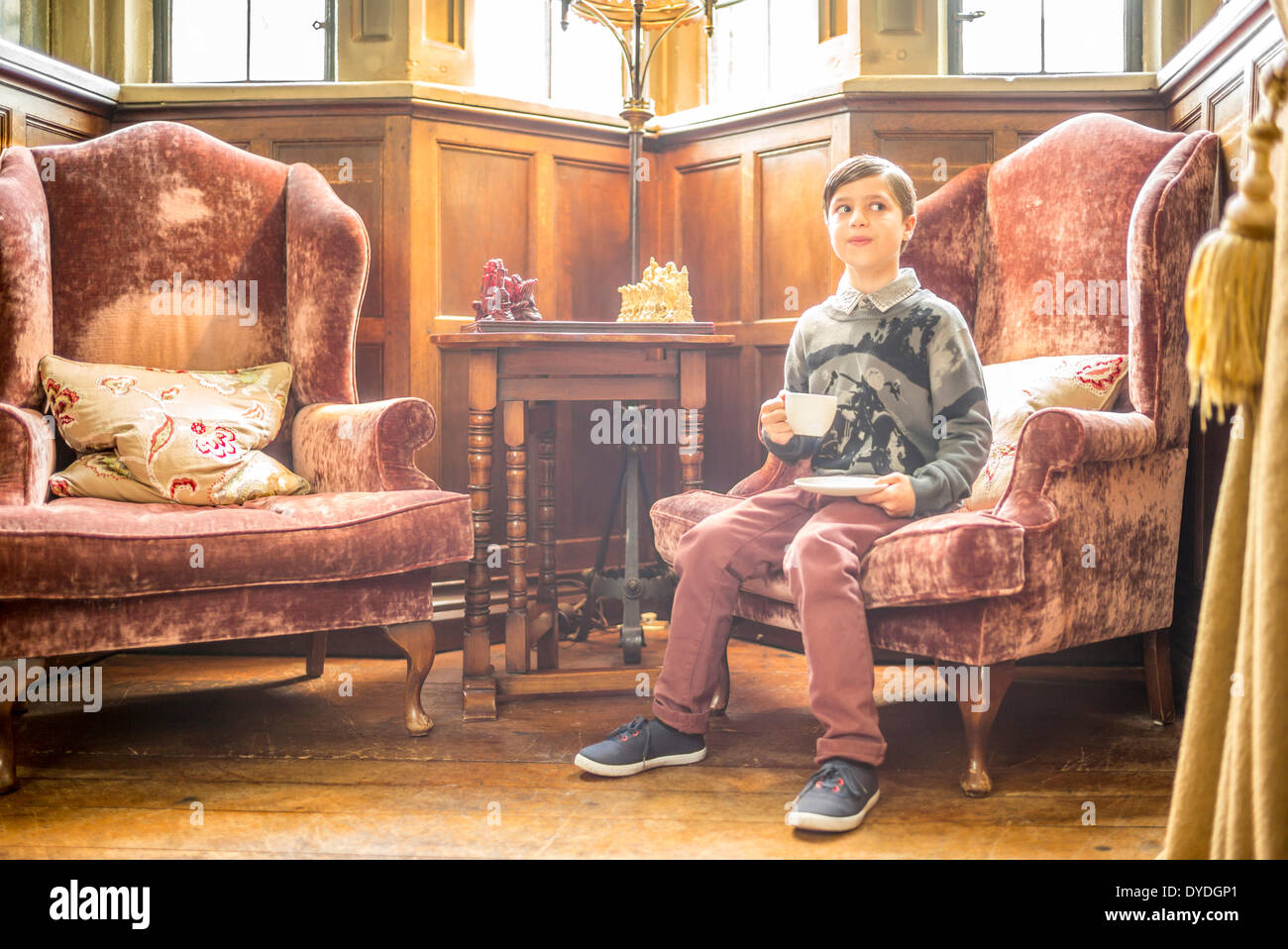 Ein Junge sitzt auf einem Stuhl in Thornbury Castle. Stockfoto
