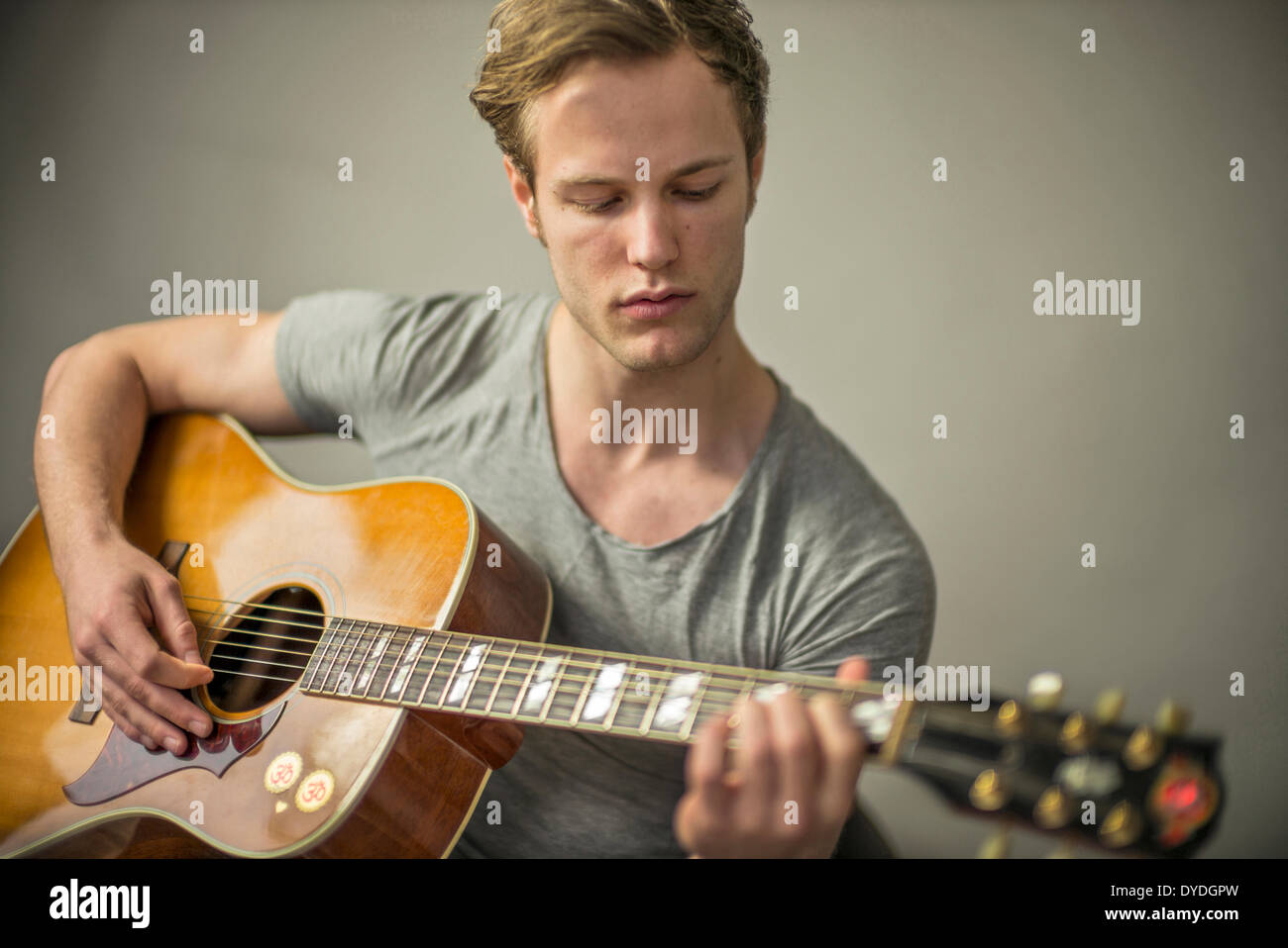 Ein schöner junger Mann spielt akustische Gitarre. Stockfoto