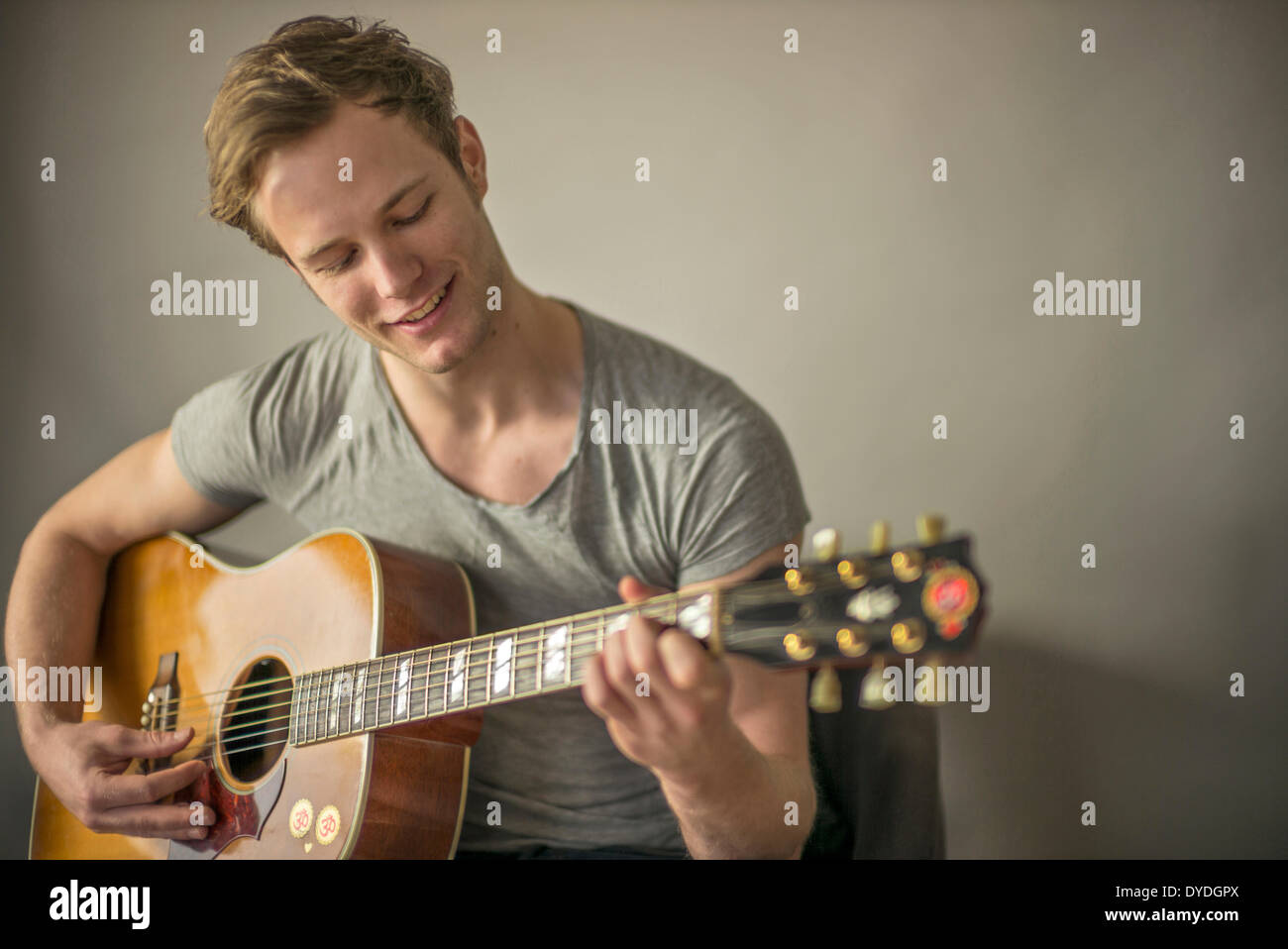 Ein schöner junger Mann spielt akustische Gitarre. Stockfoto