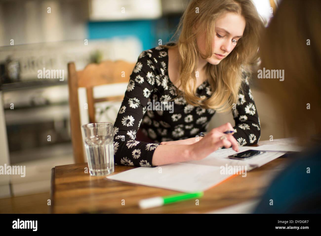 Ein 16 Jahre altes Mädchen Mathe Hausaufgaben auf dem Küchentisch. Stockfoto