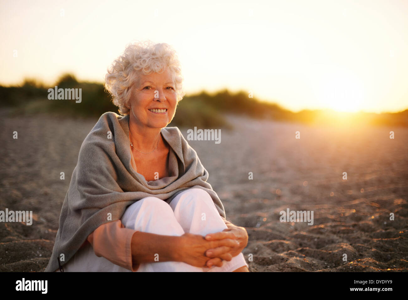 Porträt von lächelnden alte Frau am Strand sitzen. Senior kaukasischen Frauen entspannen im freien Stockfoto