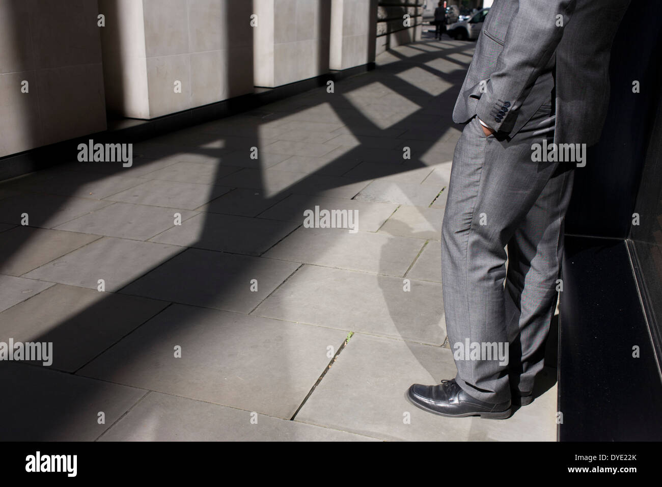 Anonyme Mann glänzend grauen Anzug steht in sonnigen Gasse in der City of London. Stockfoto