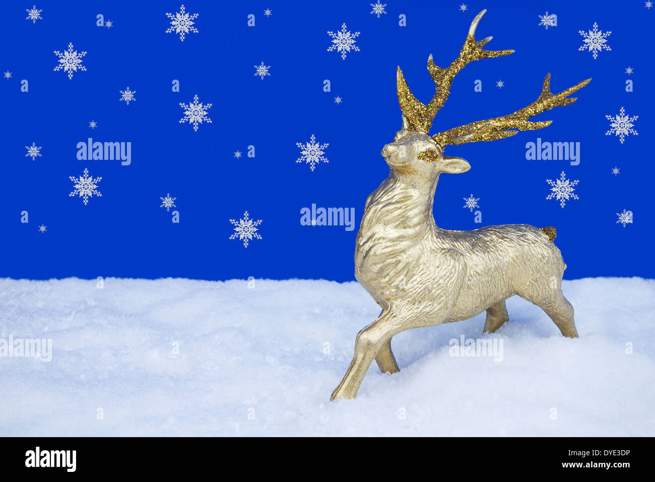 Gold Rentier Christbaumschmuck stehend auf Kunstschnee mit Schneeflocken fallen im Hintergrund Stockfoto