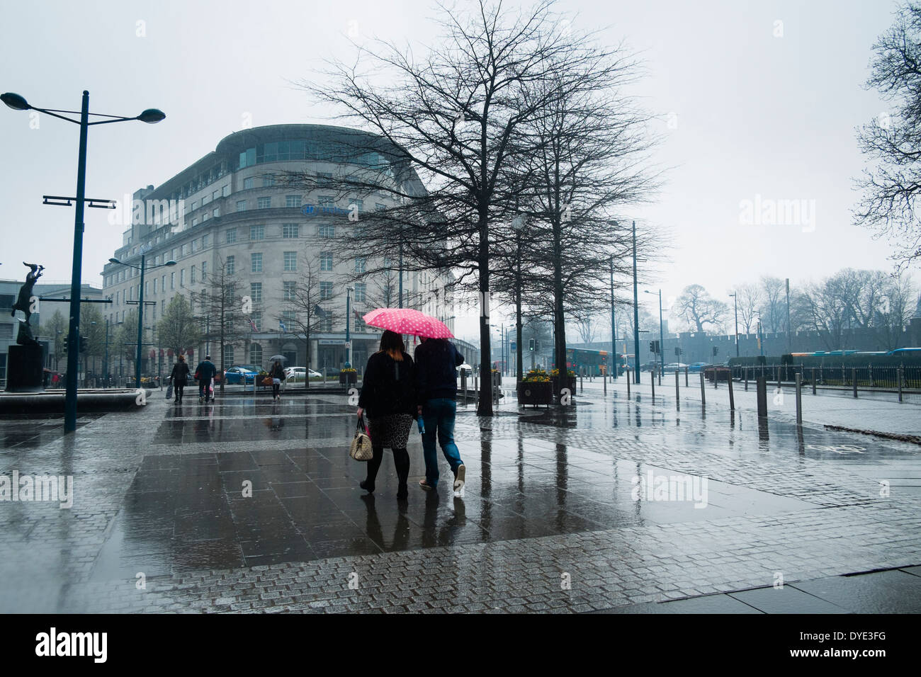 Menschen wandern in den Regen mit Sonnenschirmen, Cardiff City centre 28. März 2014 Stockfoto