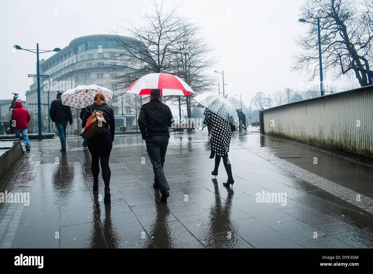Menschen wandern in den Regen mit Sonnenschirmen, Cardiff City centre 28. März 2014 Stockfoto