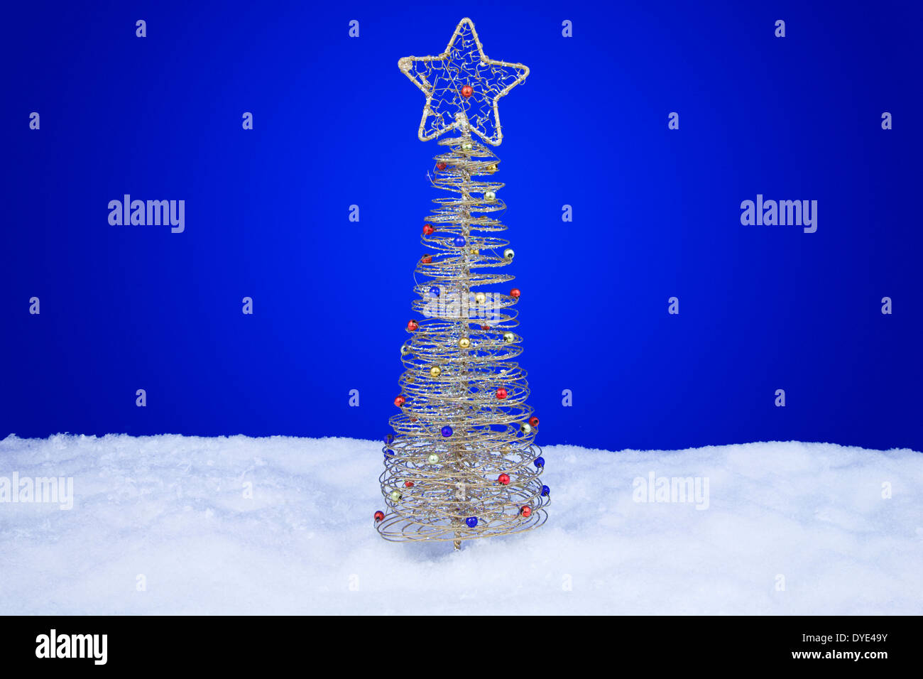 Nahaufnahme eines Gold farbigen Draht Baumes Christbaumschmuck auf blauem Hintergrund Stockfoto